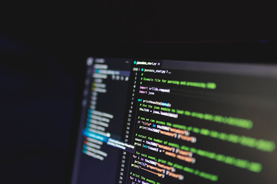 A close-up view of a computer screen displaying lines of code in a dark environment, with text in various colors including green, white, and orange. The code appears to be related to programming or sc